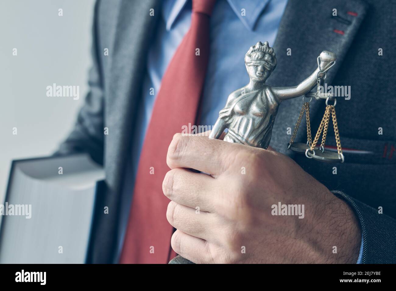 Avocat tenant le livre de droit et la statue de la Justice Lady, gros plan de la main avec une attention sélective Banque D'Images