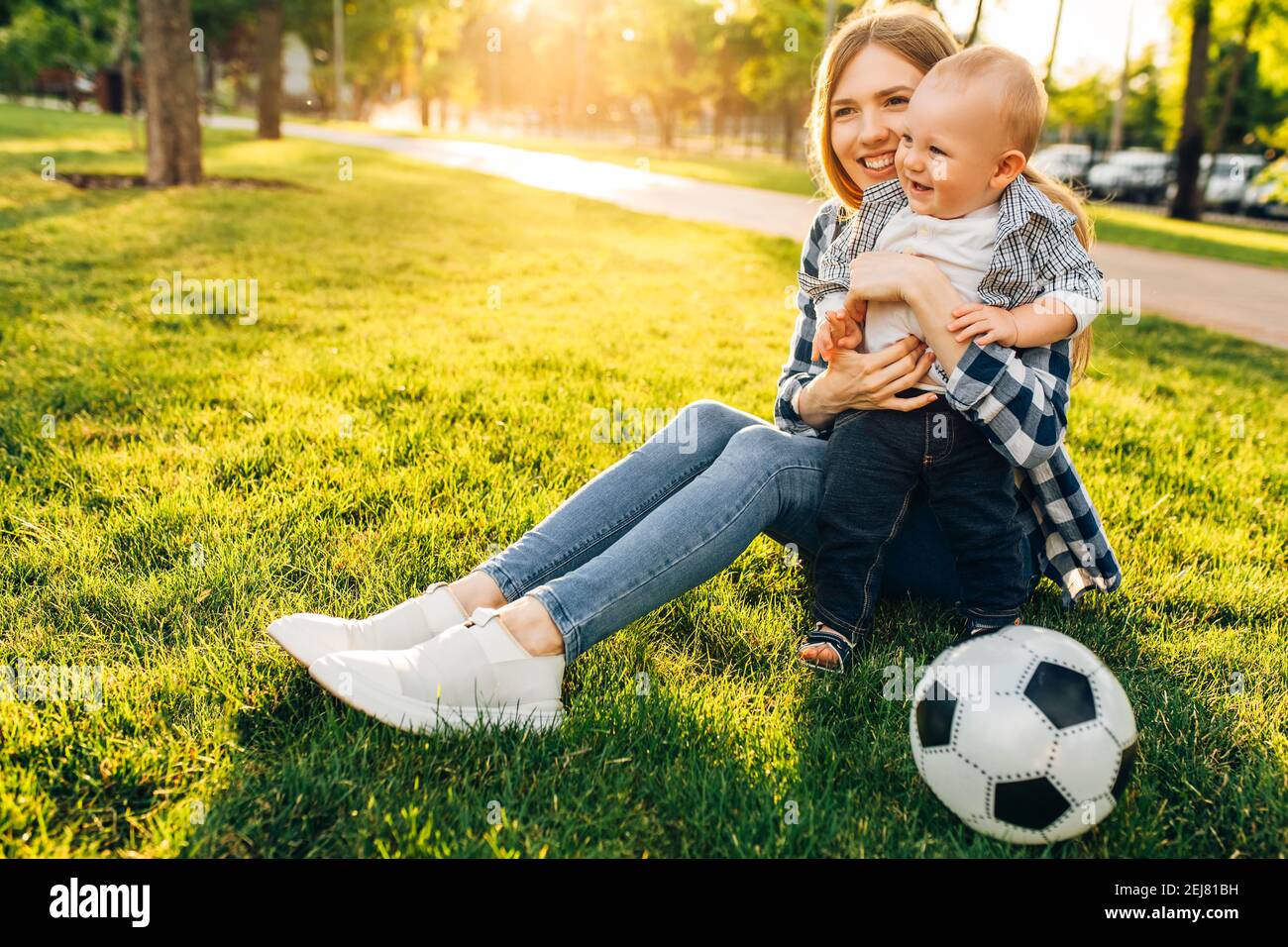 Une jeune maman heureuse et son petit fils jouent au football ensemble plein air dans le parc Banque D'Images