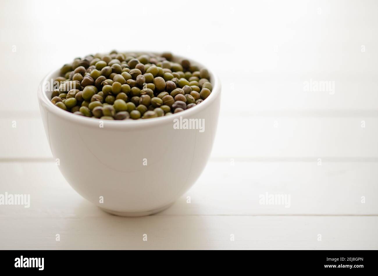 Mung de haricots dans un bol blanc sur fond blanc. Banque D'Images