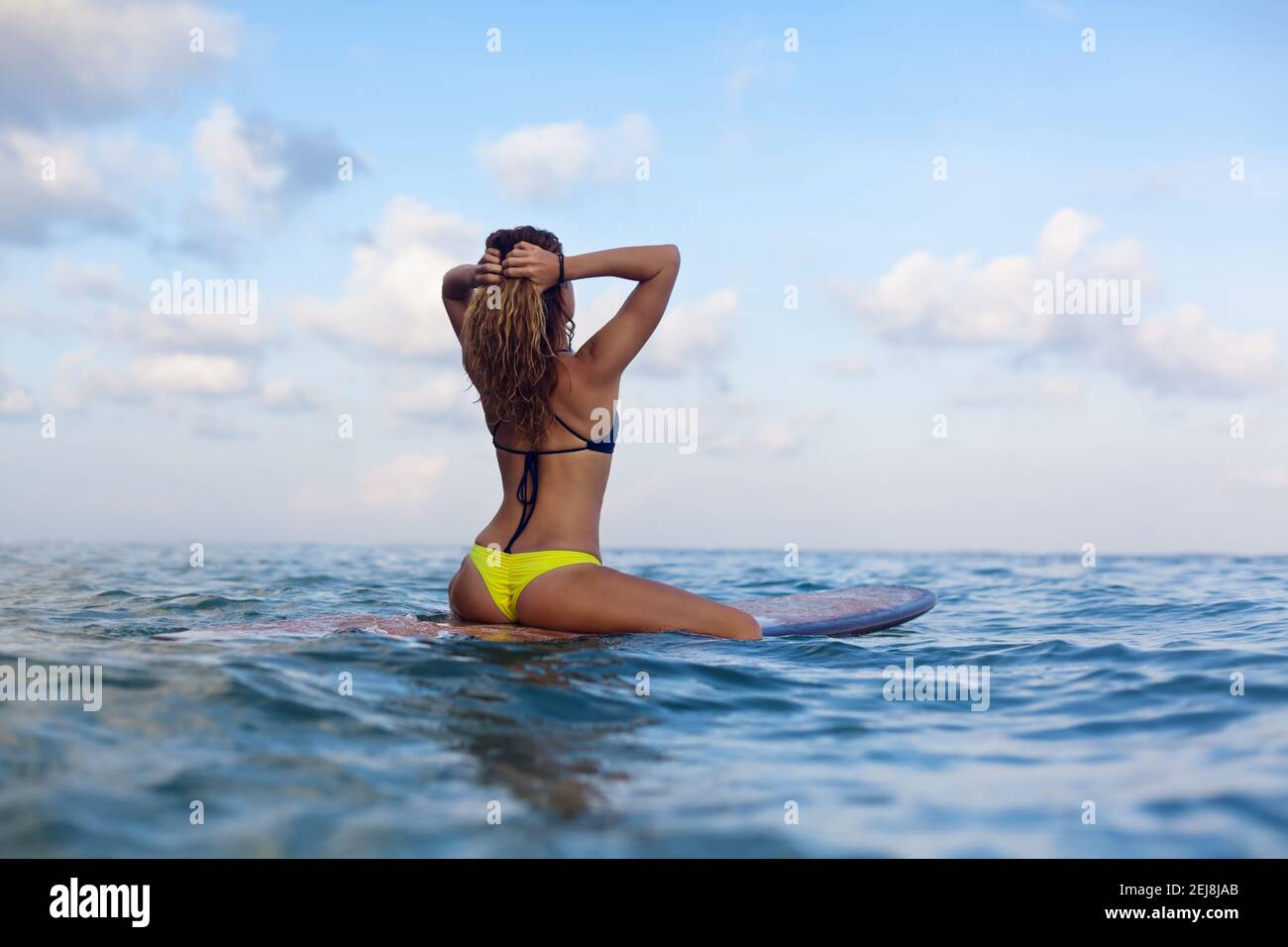 Bonne fille dans le bikini s'amuser avant de surfer surfer surfer sur  planche à voile, regarder le ciel de coucher de soleil. Les gens dans le  camp d'aventure de sport aquatique, l'activité