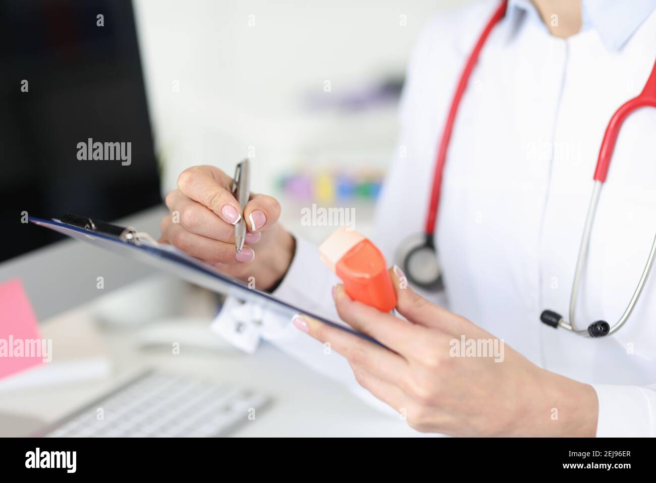 Médecin tenant l'inhalateur dans ses mains et écrivant des antécédents médicaux gros plan Banque D'Images