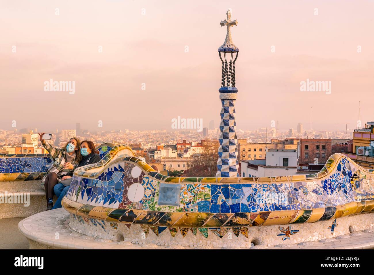 Deux femmes portant des masques chirurgicaux parlant selfie avec smartphone au coucher du soleil à Park Guell, Barcelone, Catalogne, Espagne Banque D'Images