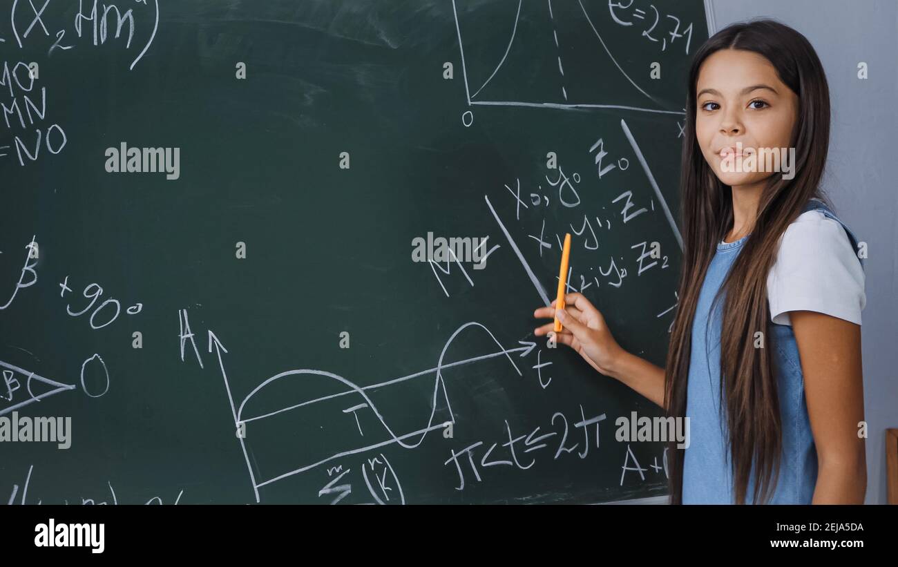 enfant tenant le stylet tout en affichant des formules mathématiques sur le tableau de surveillance Banque D'Images