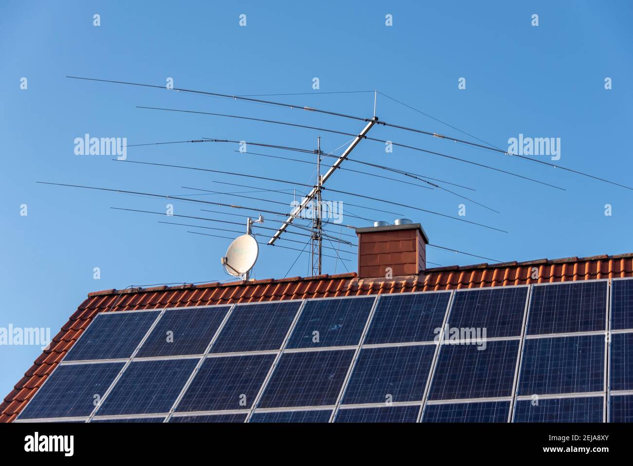 21 février 2021, Saxe-Anhalt, Wolmirstedt: Un système solaire est sur le toit d'une maison unifamiliale. Derrière elle se trouve une antenne d'un opérateur radio amateur. Photo: Stephan Schulz/dpa-Zentralbild/ZB Banque D'Images