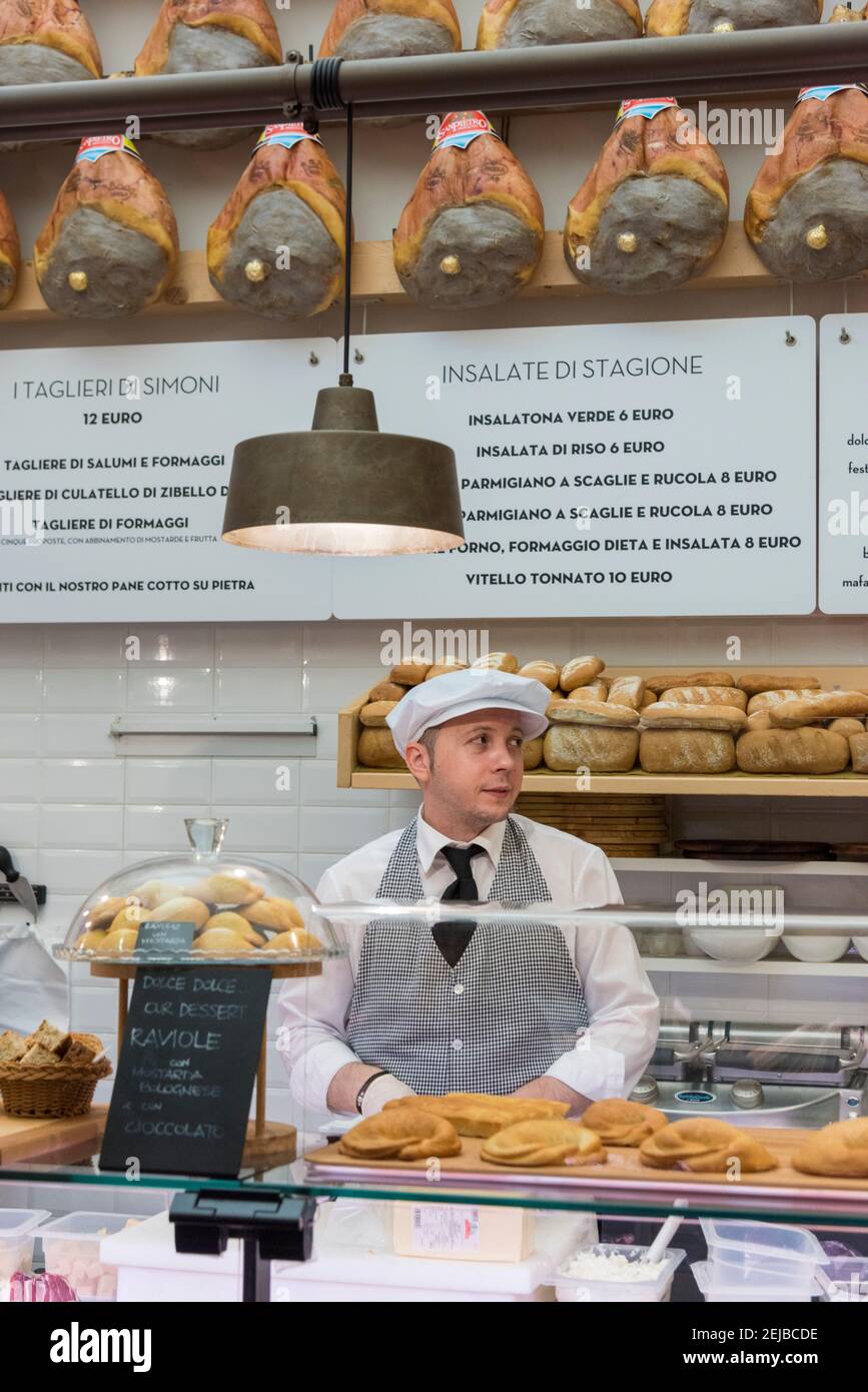 Un homme servant derrière le comptoir à la épicerie fine Simoni Vente de fromage et de jambon italiens à Bologne Italie Banque D'Images