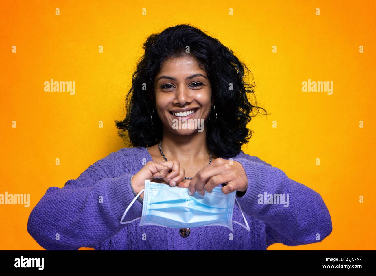 Belle jeune femme indienne se déchire sa protection de masque Covid 19 - jolie fille Sri Lanka heureuse pour la fin de la grippe pandémique fait remonter le masque du virus Banque D'Images
