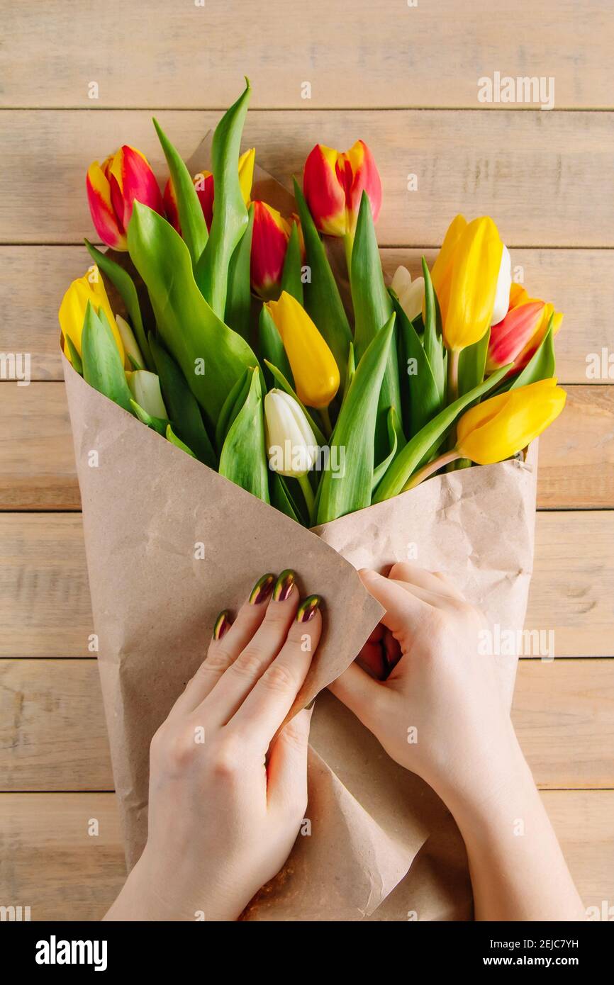 Le processus d'emballage du bouquet de tulipes fraîches dans du papier artisanal respectueux de l'environnement. Étape 2. Cadeau pour les vacances de printemps. Fleurs. Banque D'Images