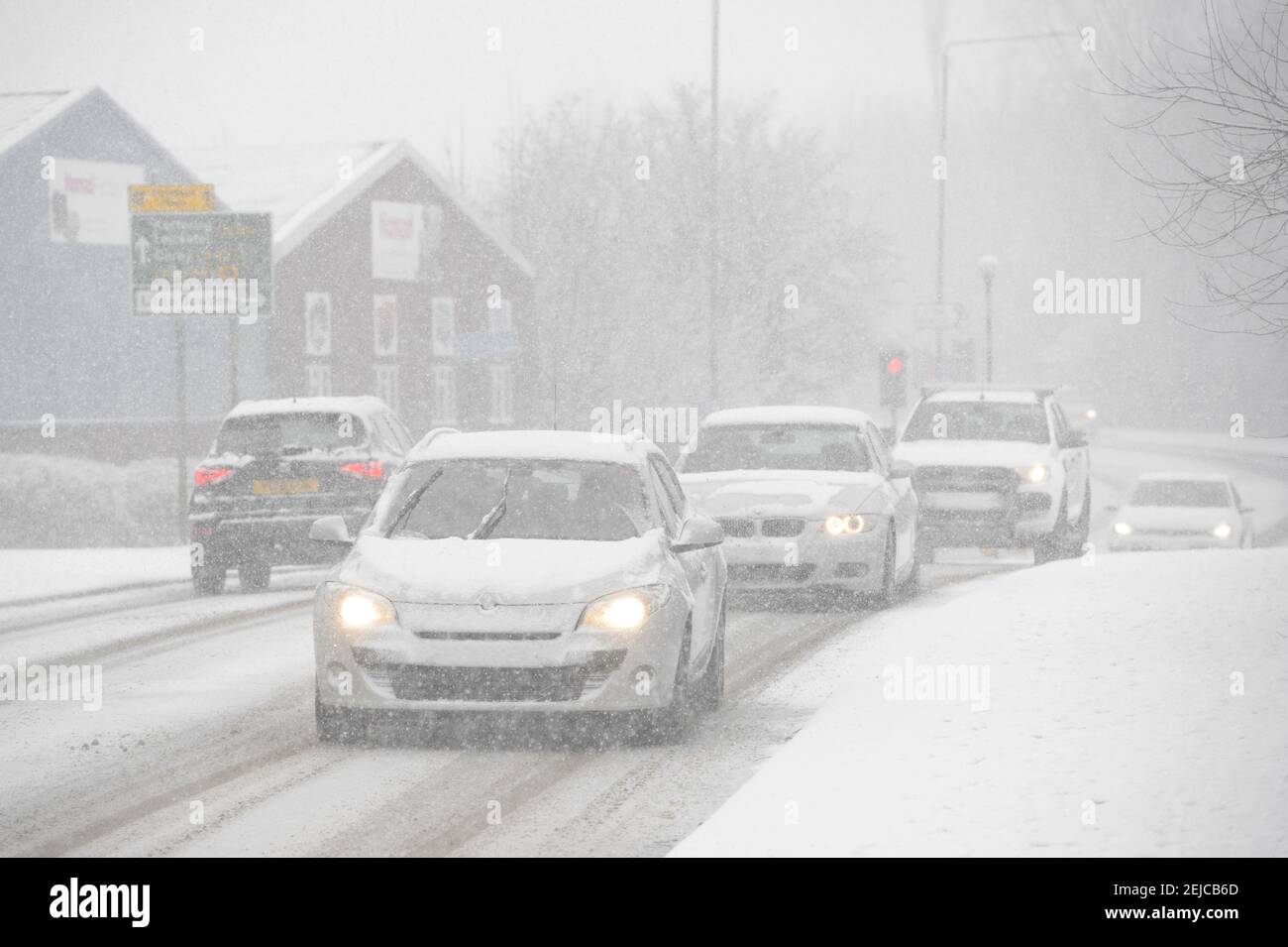 Voitures roulant sur une route enneigée par une journée d'hiver à Market Harborough, Leicestershire, Royaume-Uni. Banque D'Images