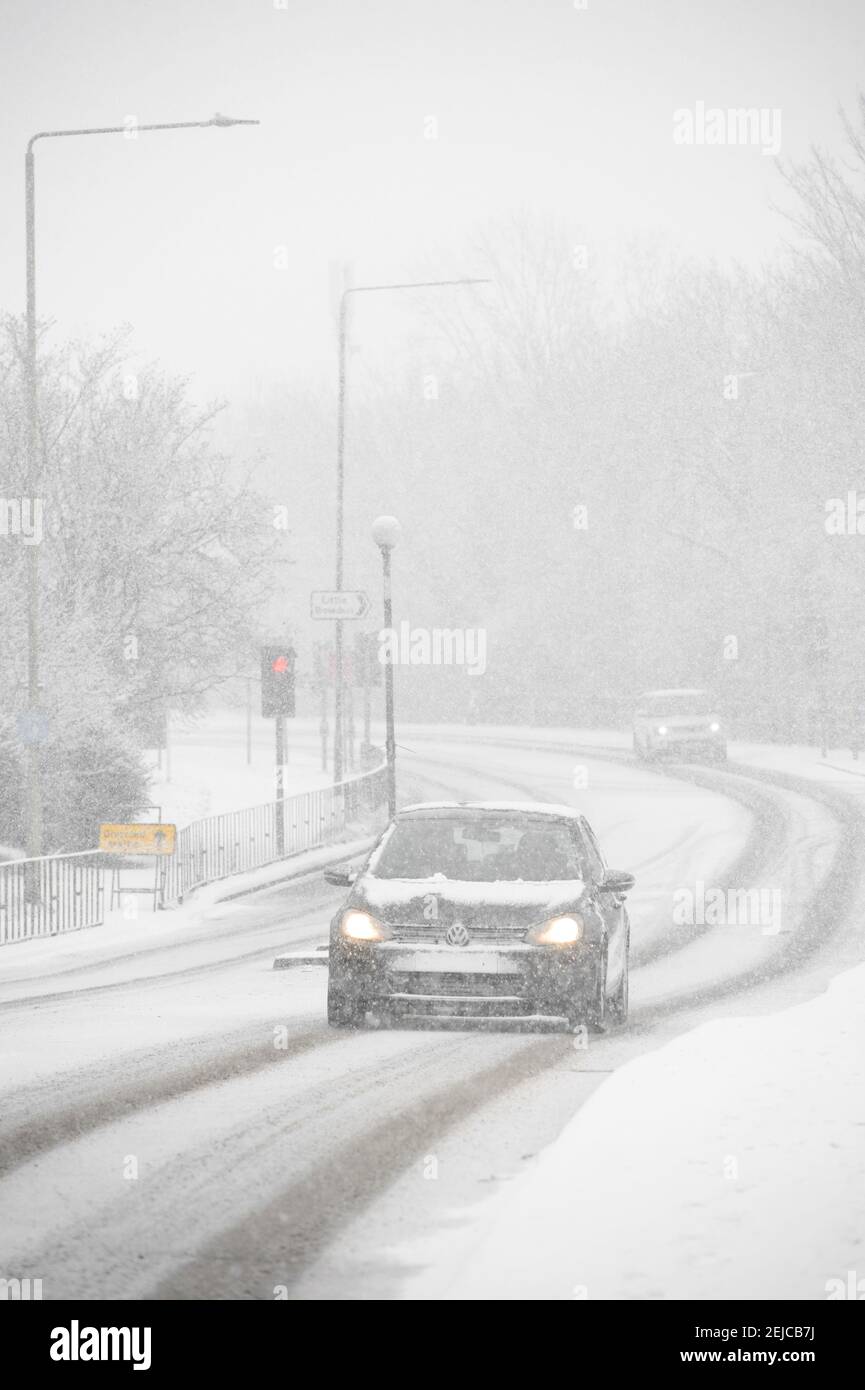 Voitures roulant sur une route enneigée par une journée d'hiver à Market Harborough, Leicestershire, Royaume-Uni. Banque D'Images