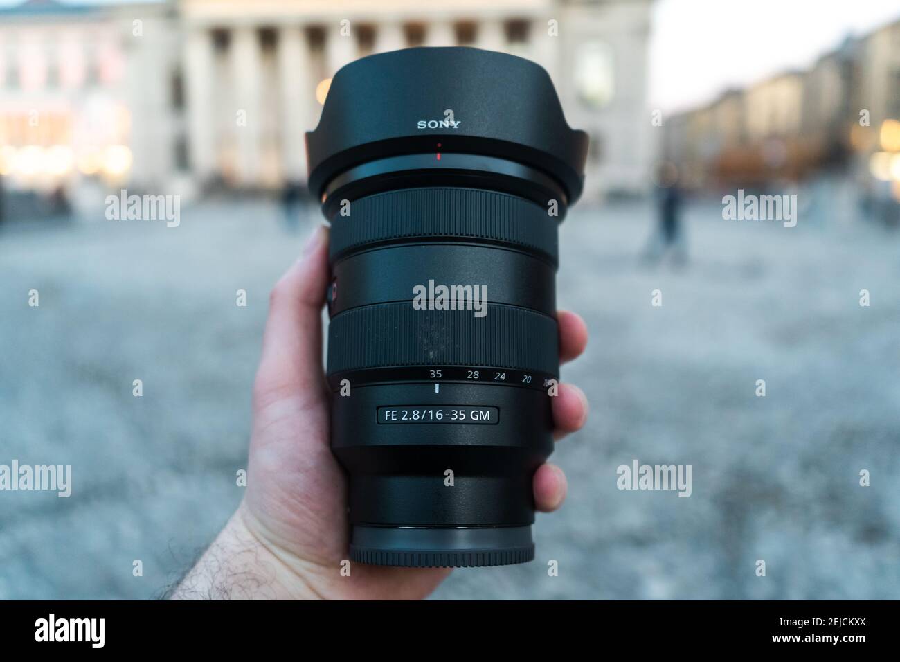 MUNICH, ALLEMAGNE - 20 février 2021 : l'objectif Sony 16-35 f2.8 GM en face d'un environnement urbain. L'objectif grand angle professionnel est tenu par une main mâle. Banque D'Images