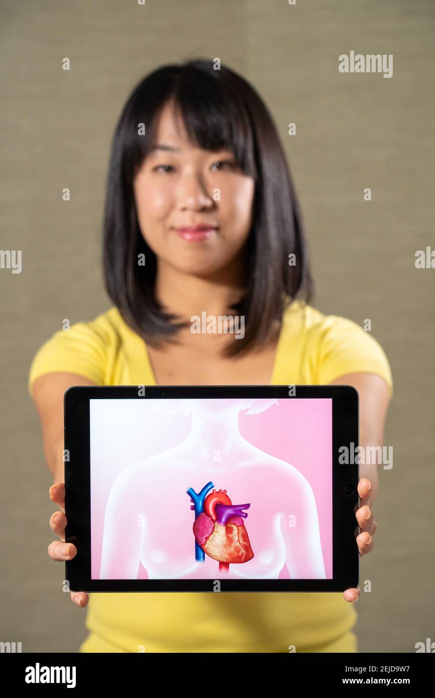 Femme tenant un écran avec un motif coeur Banque D'Images