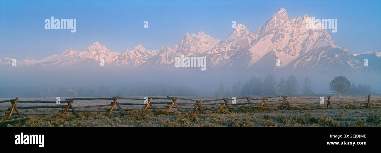 Clôture dans un champ avec une chaîne de montagnes en arrière-plan au lever du soleil, Teton Range, Grand Teton National Park, Wyoming, États-Unis Banque D'Images