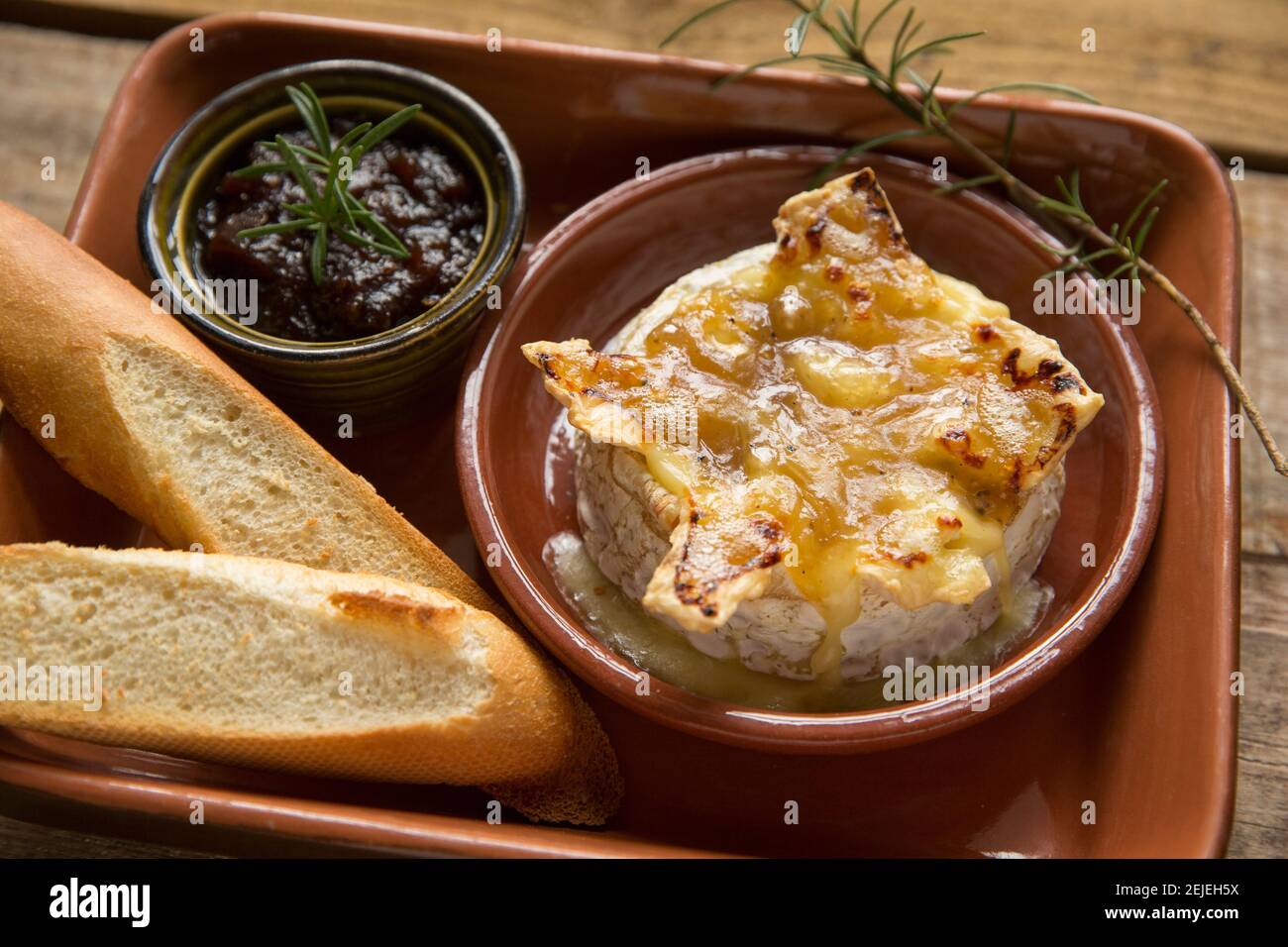 Camembert français qui a été cuit au four avec une sauce à la truffe, à l'ail et au miel, servi avec du pain français grillé et un chutney d'oignon caramélisé Banque D'Images