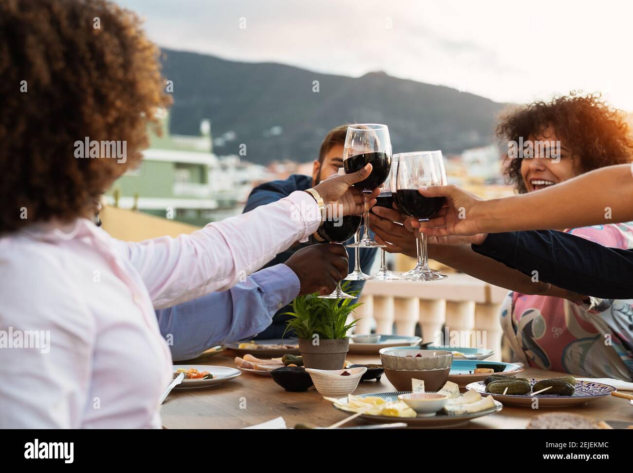 Les jeunes amis toaster avec des verres à vin rouge à l'apéritif du dîner Pendant le coucher du soleil - concept de boisson et de nourriture Banque D'Images