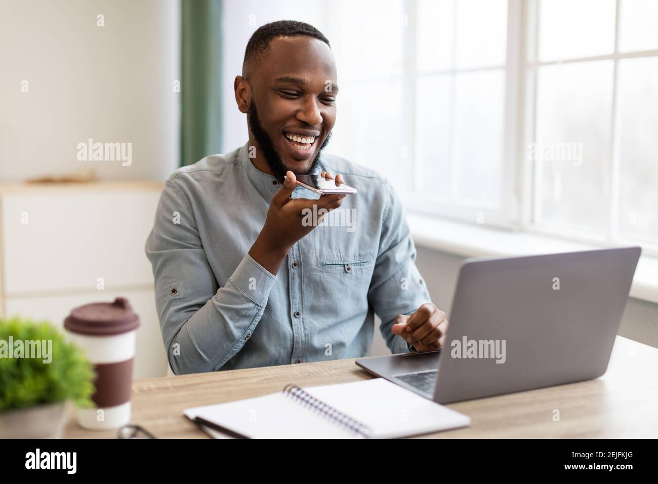 Homme d'affaires africain avec smartphone utilisant l'application Voice Assistant dans Office Banque D'Images