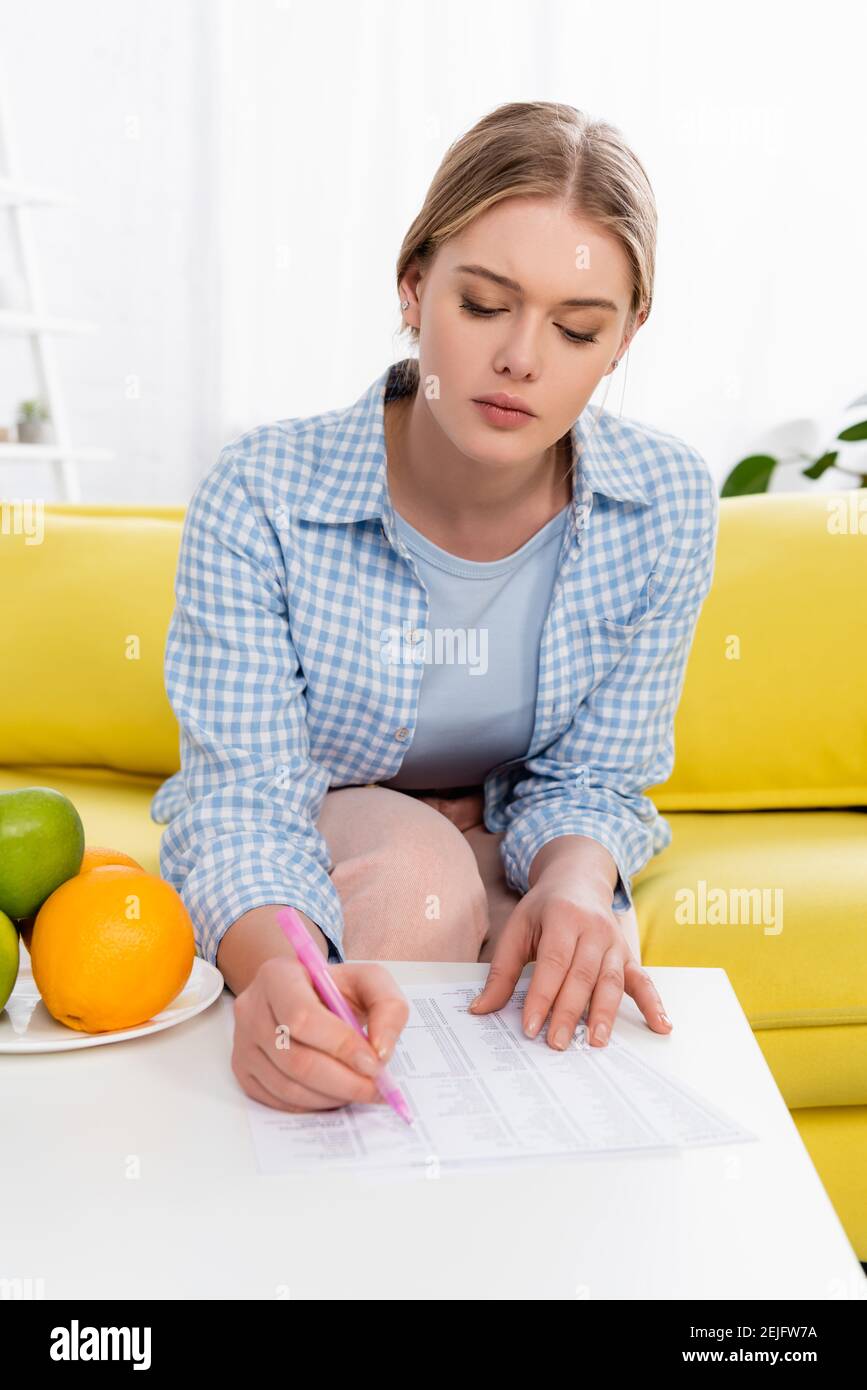 Jeune femme tenant le stylo près des papiers avec des tests d'allergie et fruits Banque D'Images