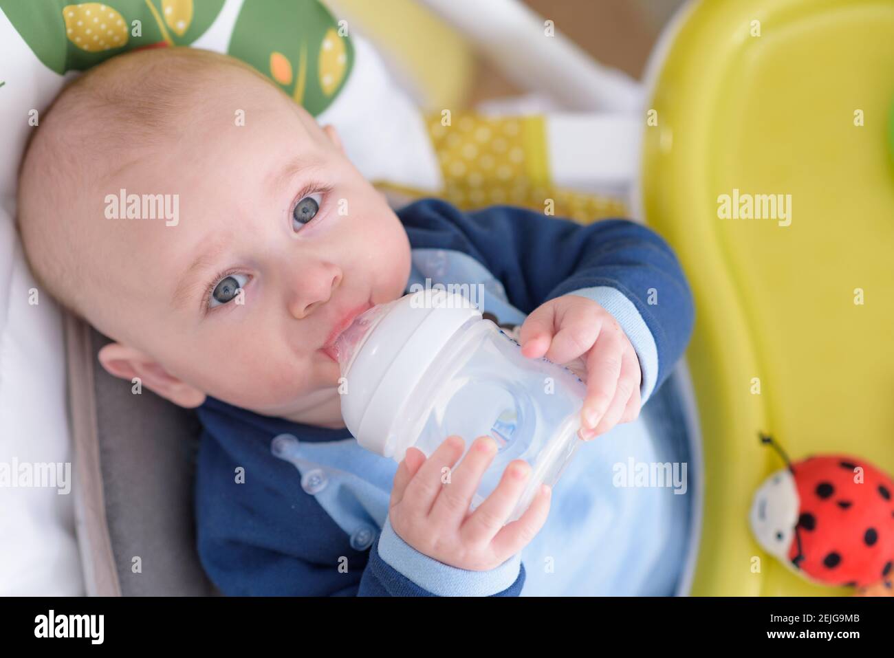 bébé souriant de 7 mois tenant une bouteille d'eau couchée Banque D'Images