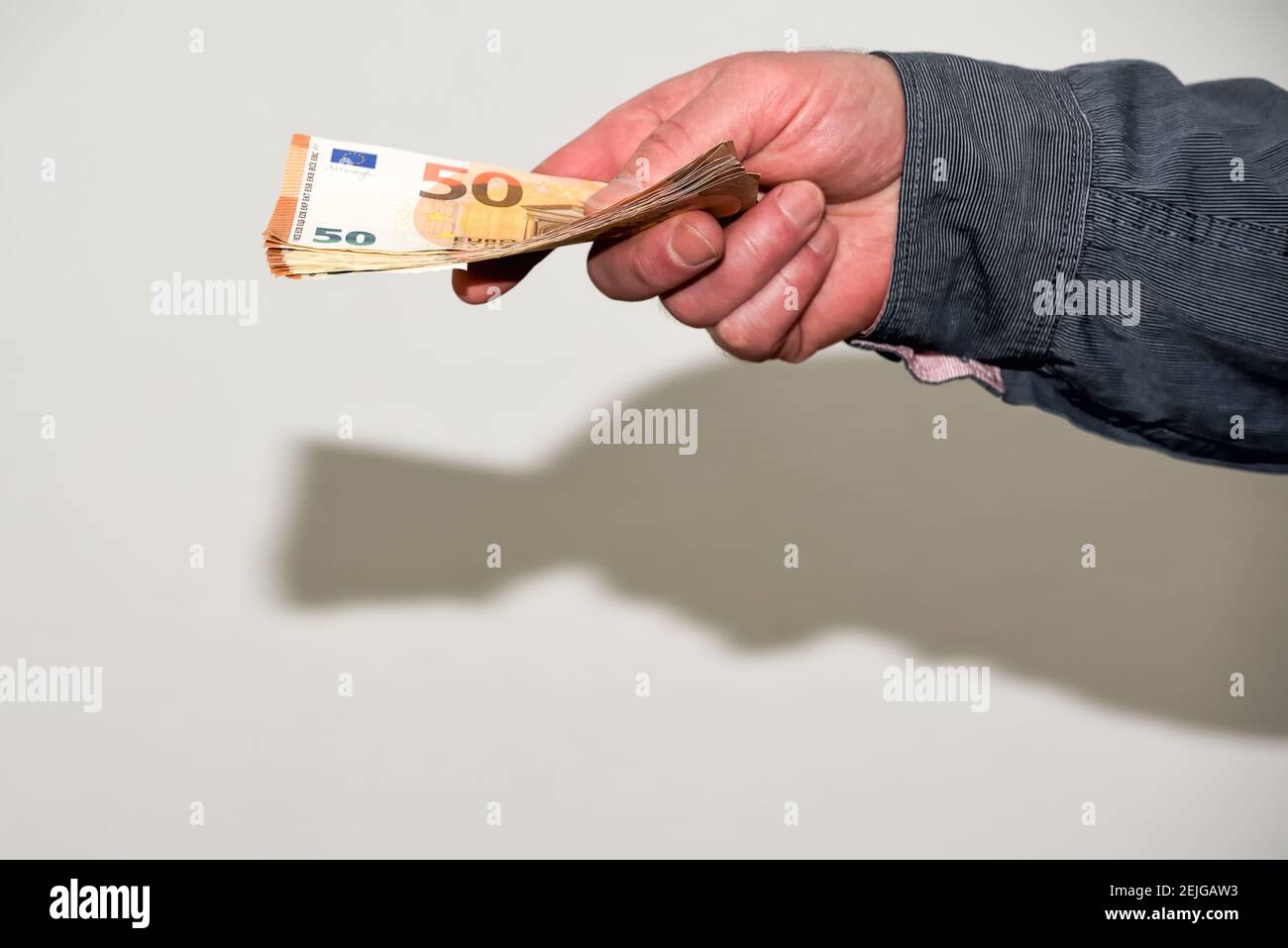 La main mâle surtendue donne une wad de billets en euros. Le travail et les transactions commerciales dans l'activité économique non déclarée de l'économie parallèle Banque D'Images