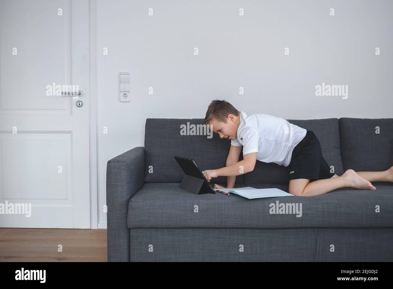 Éducation en ligne, homeschooling. Garçon d'école ayant la leçon en ligne à la maison sur l'entraîneur Banque D'Images