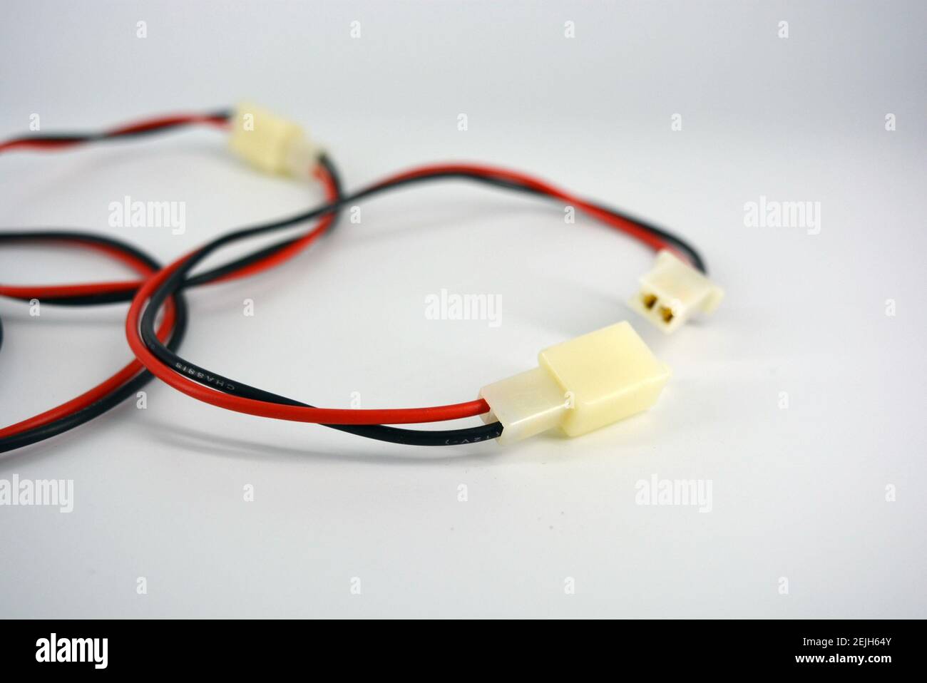 Grands fils électriques rouges noirs sur 12 V, 220 V avec connecteur DAD en plastique blanc et MOM situé sur un fond en plastique blanc. Banque D'Images