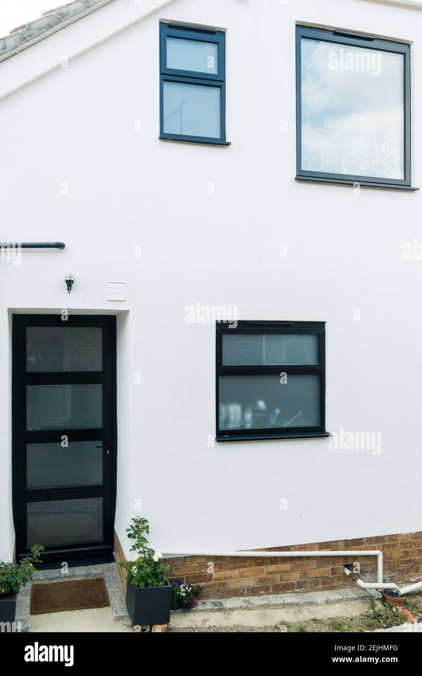 Une maison moderne typique qui a été rénovée avec un rendu blanc et des fenêtres et des portes en plastique UPVC gris foncé à double vitrage. Banque D'Images