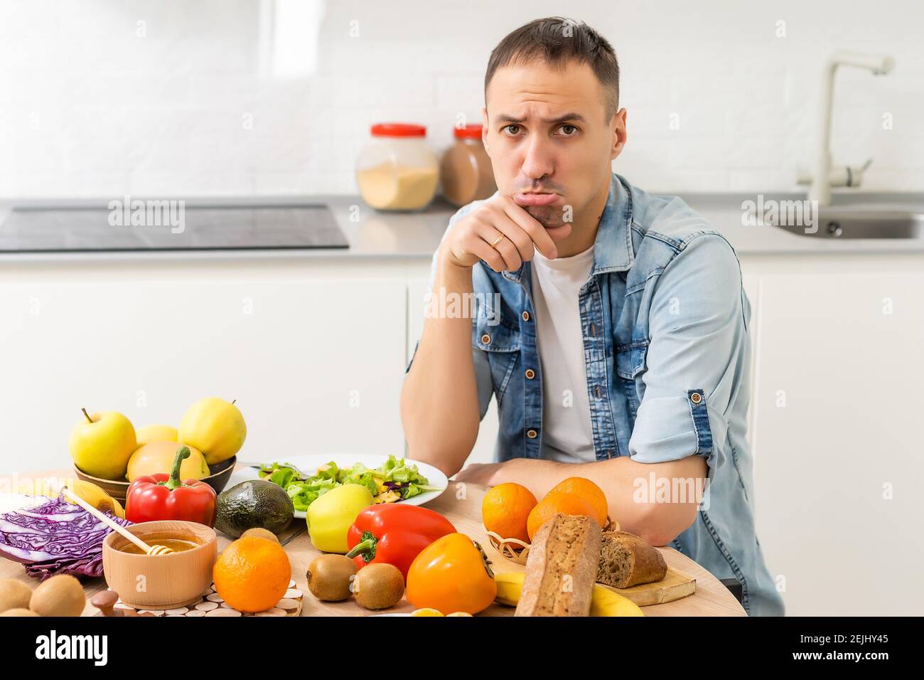 Joyeux jeune homme préparant un dîner romantique recherche de recettes de légumes Menu de régime, mari souriant cuisant la nourriture végétalienne saine salade coupée dans la cuisine Banque D'Images