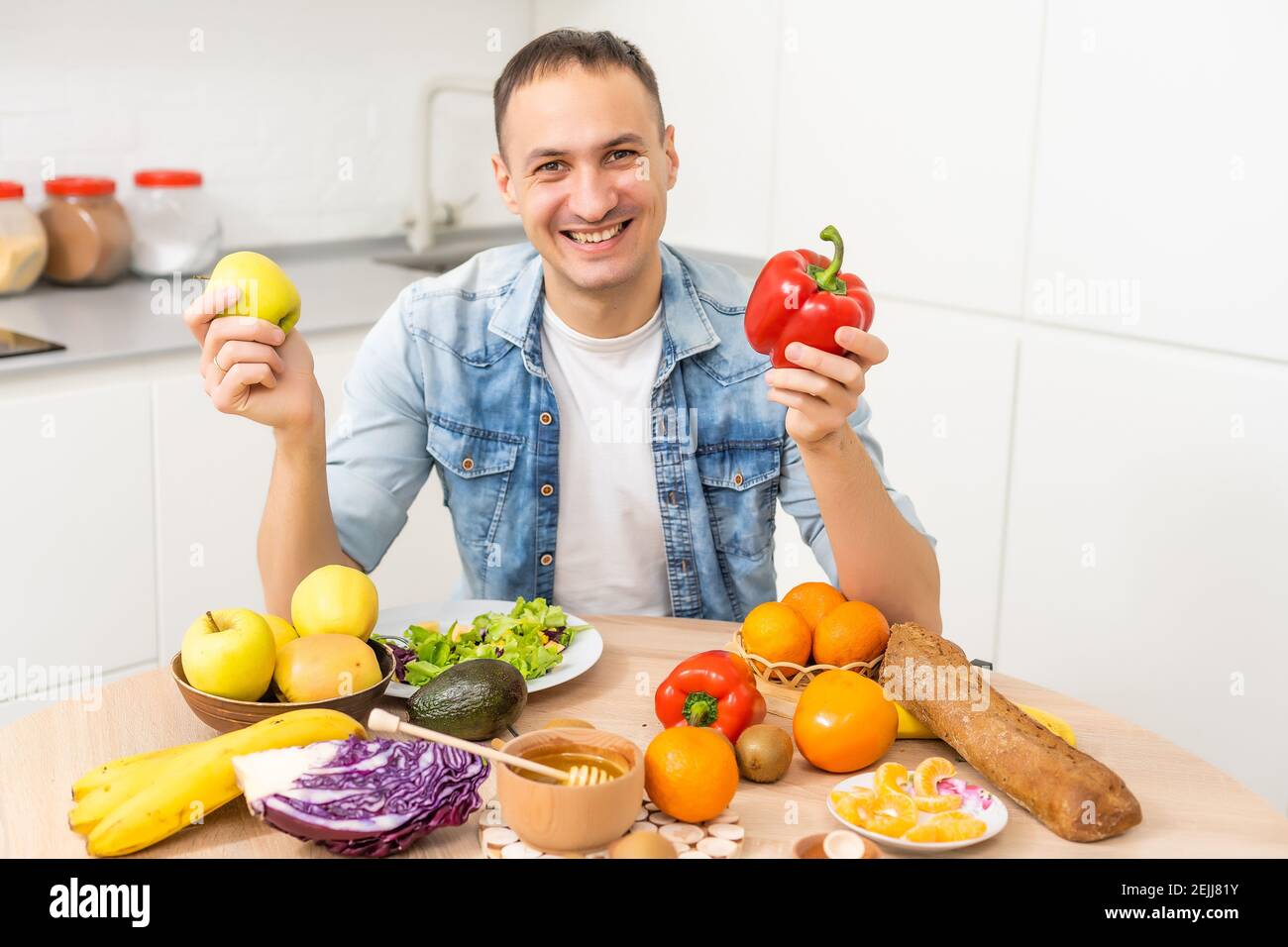 Joyeux jeune homme préparant un dîner romantique recherche de recettes de légumes Menu de régime, mari souriant cuisant la nourriture végétalienne saine salade coupée dans la cuisine Banque D'Images