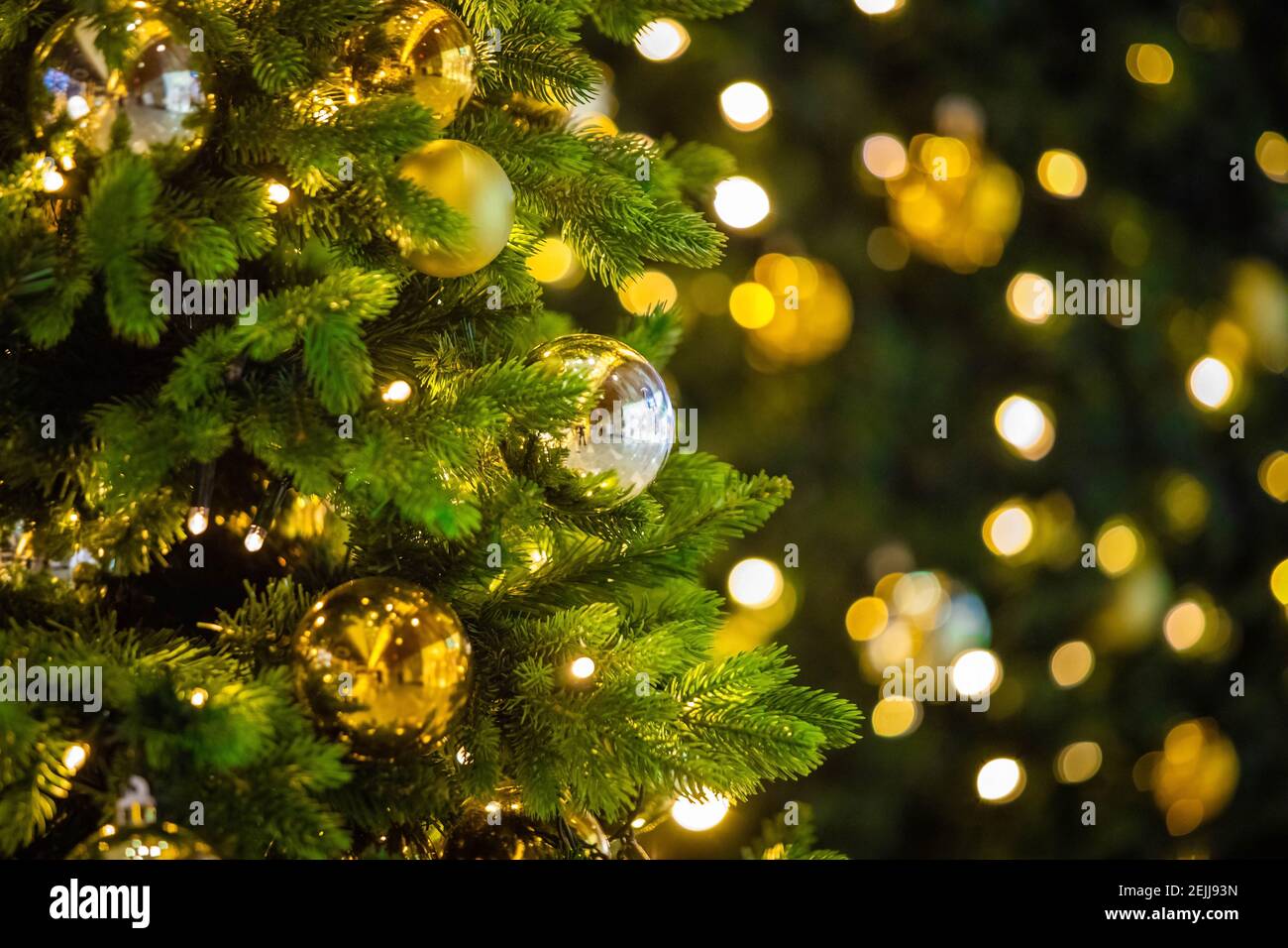 Gros plan des boules sur l'arbre de noël. Guirlande de bokeh en arrière-plan or lumière vacances conception Banque D'Images