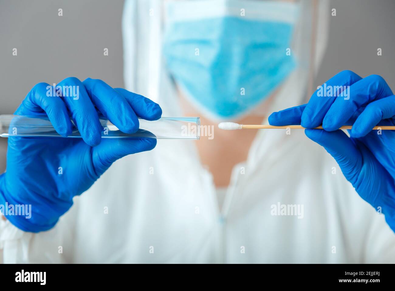 Test pcr Covid 19 dans les mains de l'infirmière. Médecin en costume de protection masque médical gants tenant un échantillon de salive Swab pour le diagnostic covid19 coronavirus virus in Banque D'Images