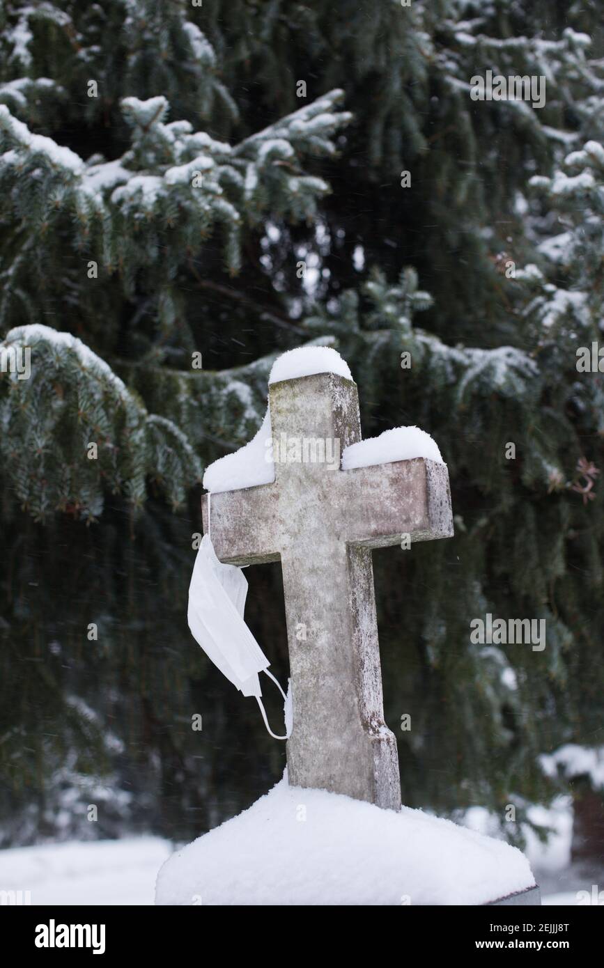 Covid 19 mort. Un masque de visage accroché à la croix dans un cimetière, cimetière. Victime du coronavirus. Pandémie dans les pays nordiques. Comment prévenir le coronavirus? Banque D'Images