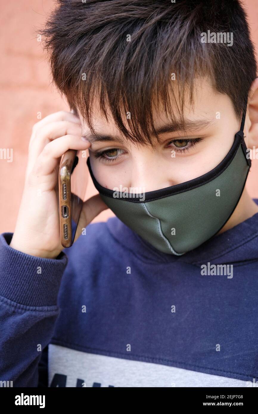 Green Eyes boy passer un appel téléphonique portant un vert masque facial Banque D'Images