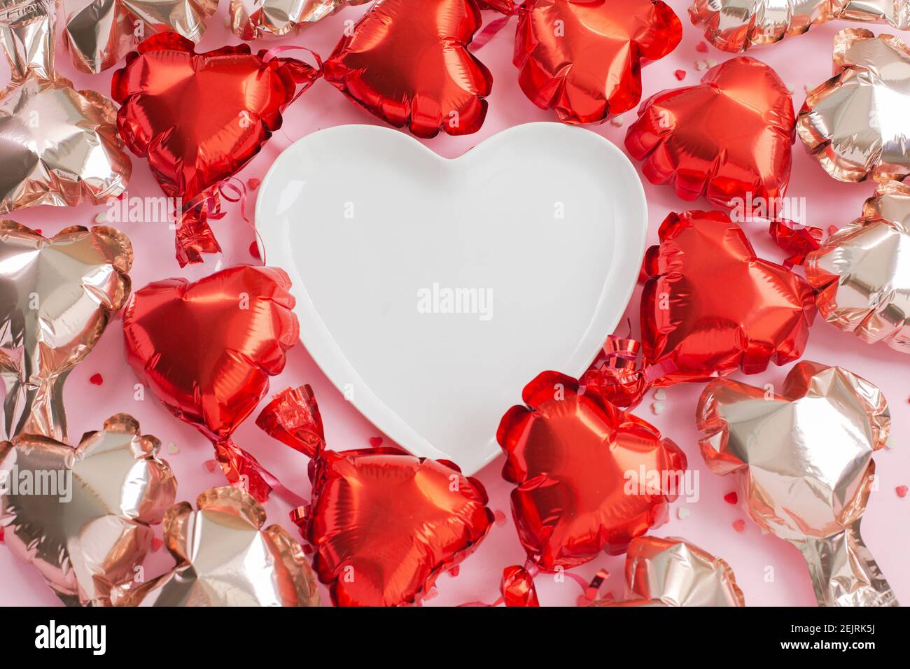 Bulles d'air de papier d'aluminium en forme de coeur autour d'une plaque en forme de coeur blanc. Concept d'amour. Fête des fêtes. Réglage de la table des congés. Saint-Valentin ou mariage Banque D'Images