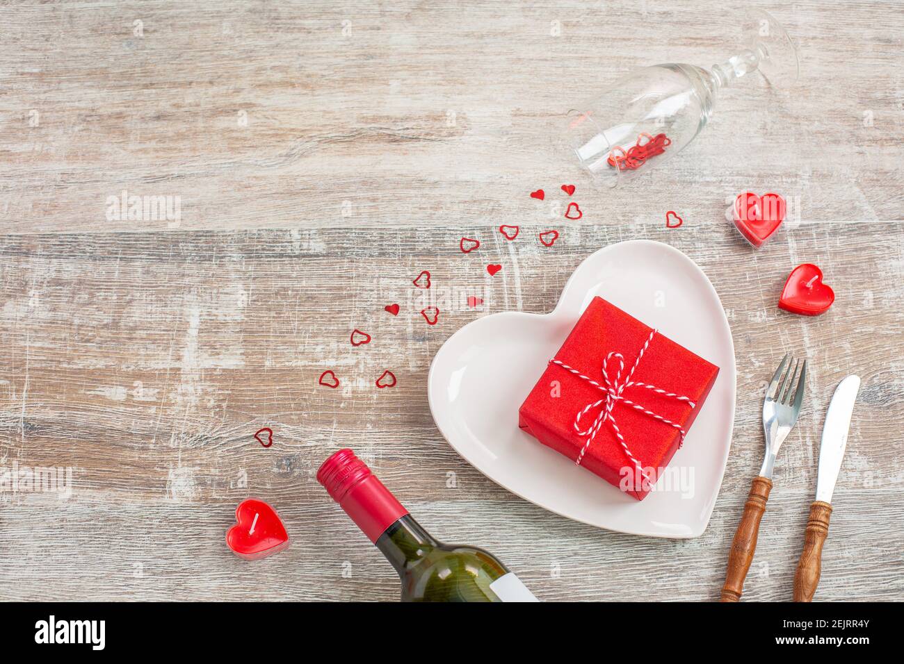 Bouteille de vin rouge et boîte cadeau amour, bougies, fleurs sur fond de bois. Saint-Valentin. Le concept de vacances et d'amour. Pose à plat Banque D'Images