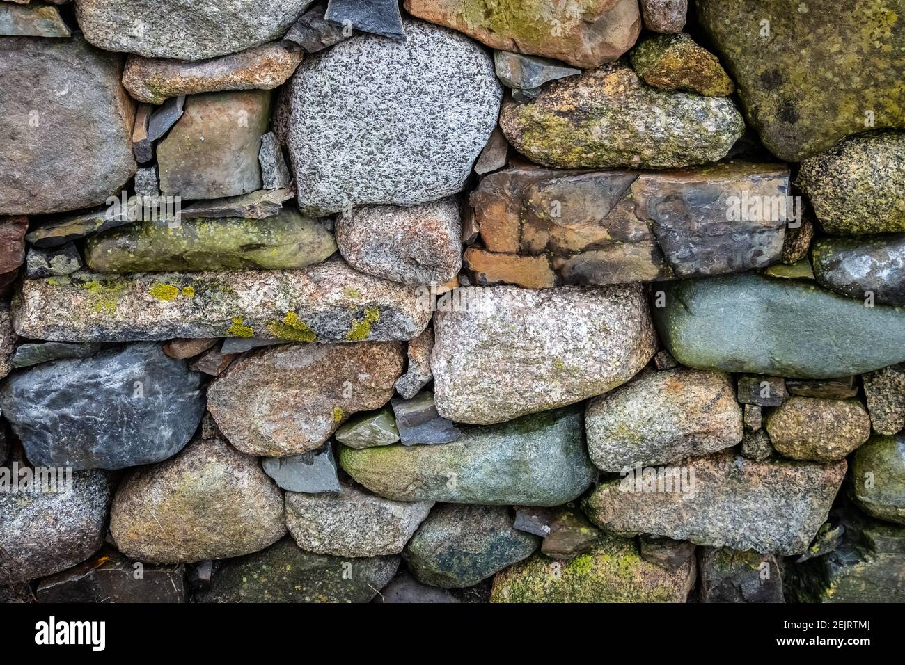 Un gros plan d'un ancien Rock Seawall empilé à la main dans la lumière de l'été de l'après-midi. Banque D'Images