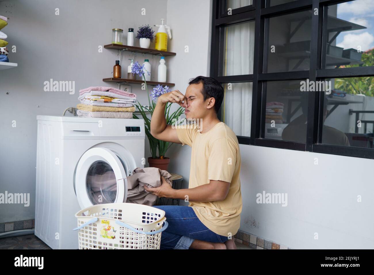 asiatique homme faisant du linge à la maison chargement des vêtements dans  la machine à laver mauvaise odeur. Odeur mal Photo Stock - Alamy