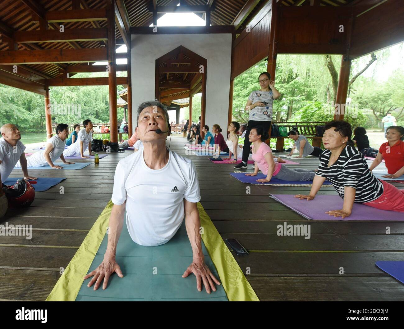 Zhejiangï¼ŒCHINA-le 17 mai 2020, 'yoga grandpa' leming chao enseigne des cours de yoga gratuits aux touristes sur la rive du lac ouest à hangzhou, dans la province de zhejiang en Chine orientale. Le mingchao, connu sous le nom de « grand-père du yoga », a commencé sa première classe publique de yoga en 2020 sur la rive du lac ouest à hangzhou, attirant de nombreux touristes à pratiquer le yoga avec les personnes âgées pour améliorer leur forme physique. Il est entendu que le mingchao, 76 ans de cette année, a pris sa retraite du sol zéro, grâce à huit années d'entraînement au yoga dur pour obtenir la certification d'instructeur de yoga senior. Et le vieil homme Banque D'Images