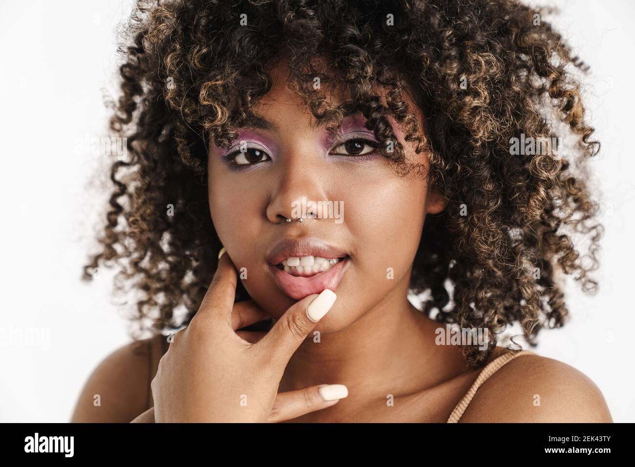 Belle fille afro-américaine avec piercing touchant ses lèvres isolées sur  fond blanc Photo Stock - Alamy