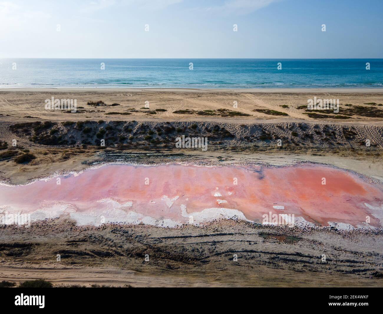 Pink Lake à Ras al Khaimah entouré par le bord de mer et l'eau de la crique, le désert des cotisations de sable et les montagnes montagnes dans les Émirats arabes Unis offre à marché unique Banque D'Images