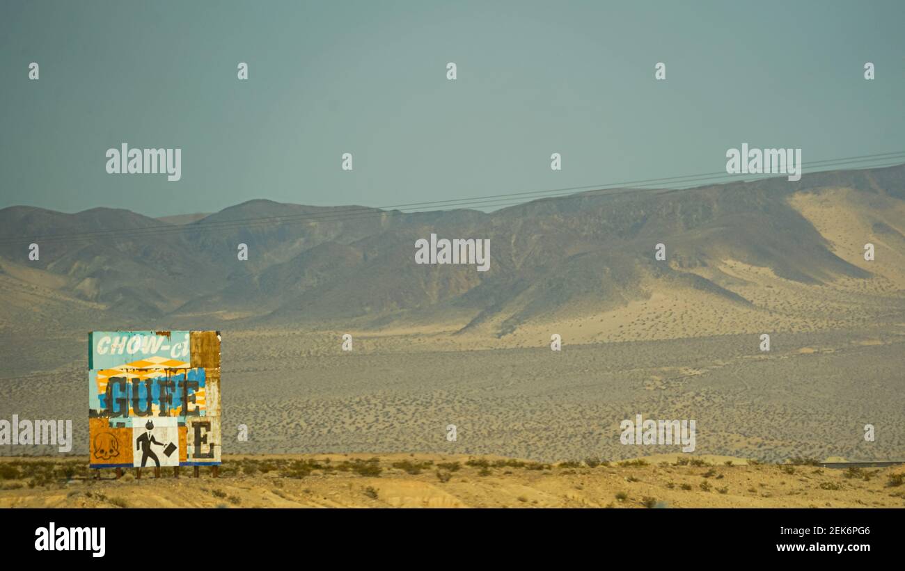 Vieux panneau publicitaire traversé par la route en Californie désert Banque D'Images