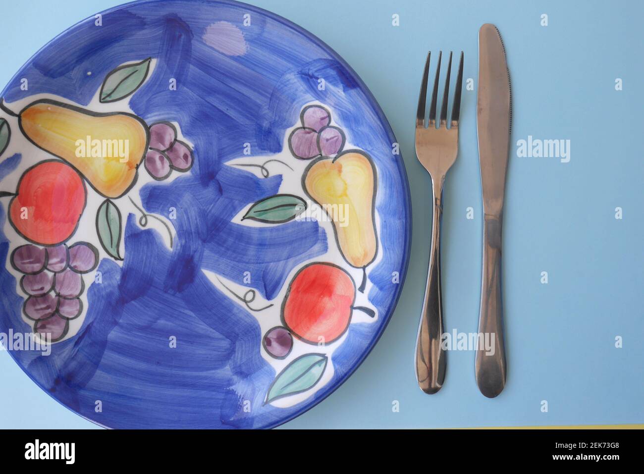 Assiette à dîner en céramique vide avec motif fruits, couteau et fourchette Banque D'Images