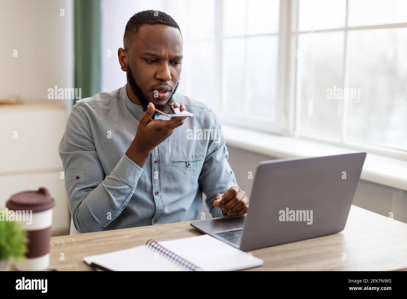 Homme d'affaires noir utilisant le téléphone avec l'application Voice Assistant dans Office Banque D'Images