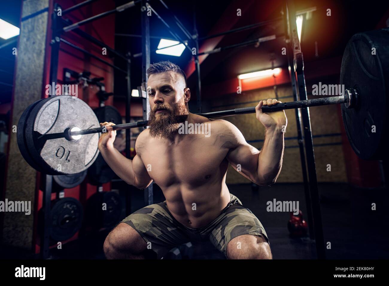 Homme sportif robuste barbu qui pèse lourd dans une pièce sombre. Banque D'Images