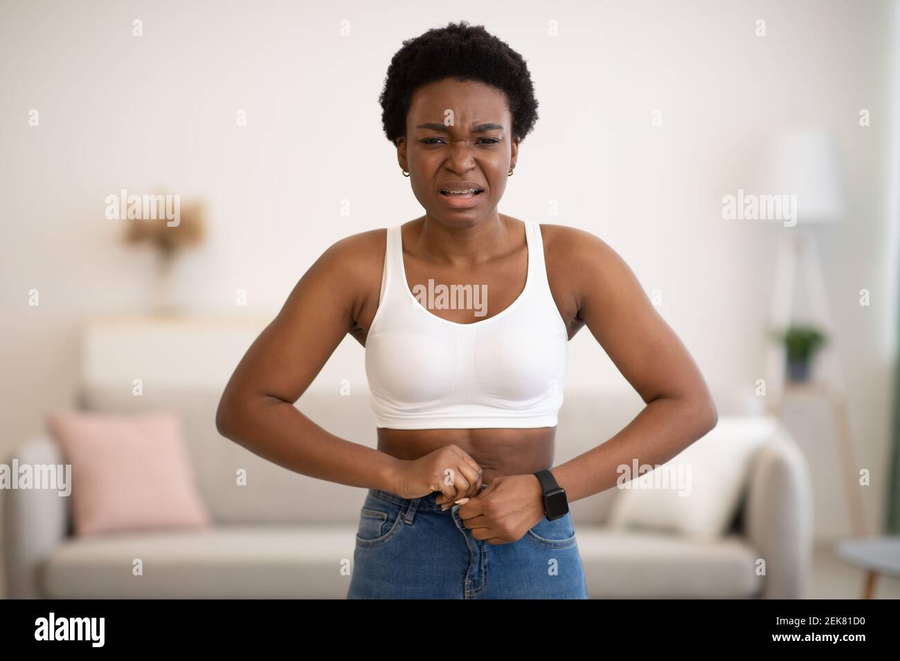 Femme noire frustrée fesses petits jeans après le gain de poids à l'intérieur Banque D'Images