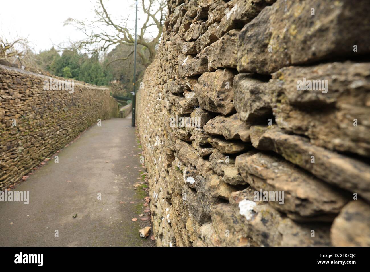 Vieux mur en pierre sur le côté d'une passerelle piétonne Banque D'Images
