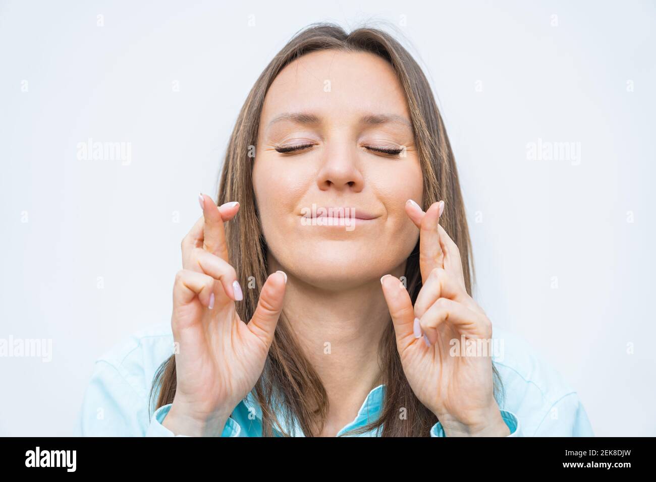 Jeune femme d'affaires souriant avec les yeux fermés et croisant les doigts. Je souhaite Bonne chance. Le rêve devient réalité, se demandant le mieux Banque D'Images