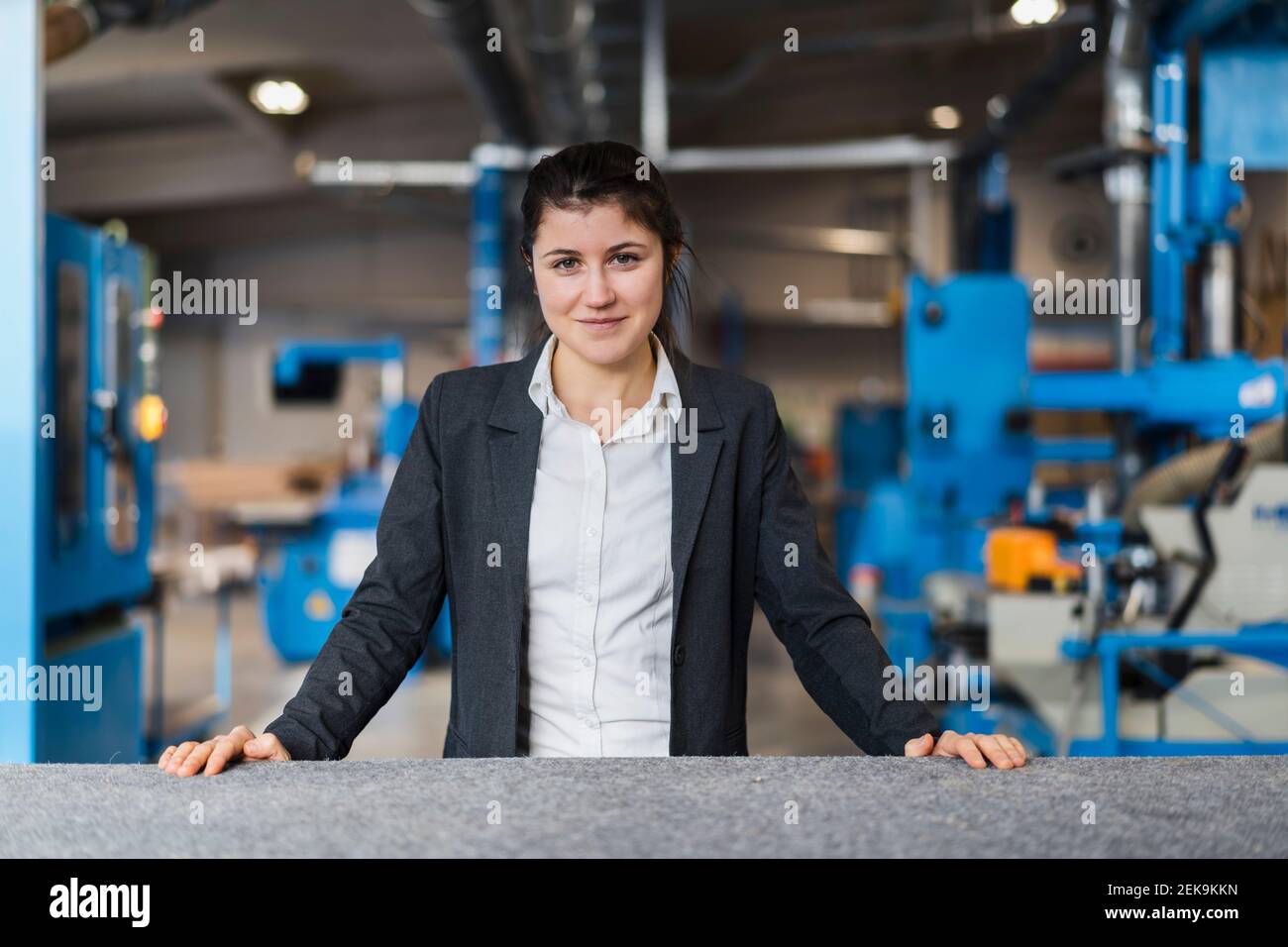 Jeune femme d'affaires souriant en se tenant dans l'industrie Banque D'Images