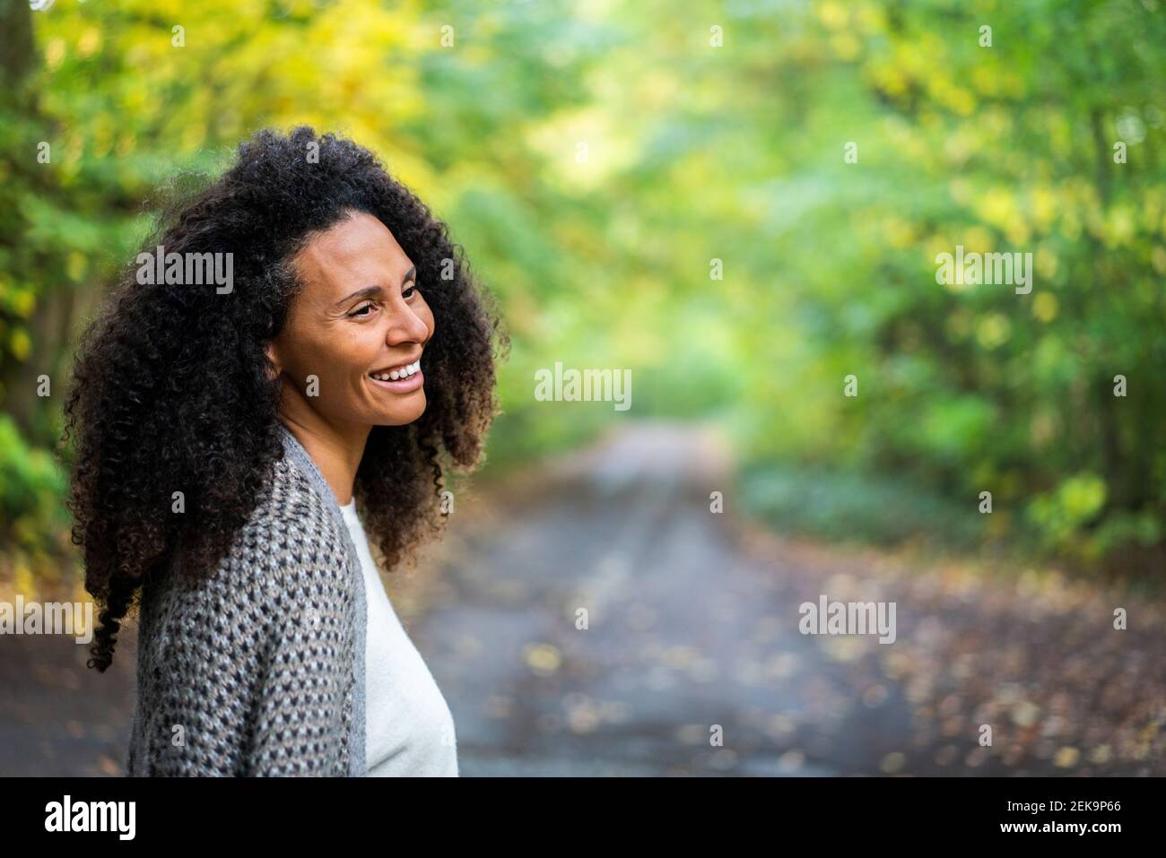 Happy woman looking away while standing in forest Banque D'Images