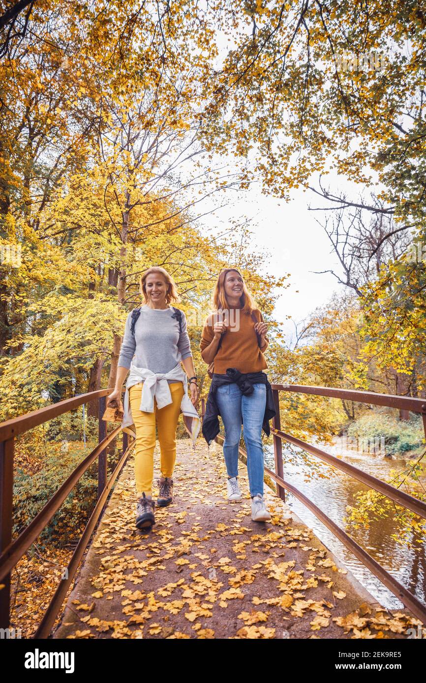 Femmes souriant en marchant sur le pont en forêt Banque D'Images