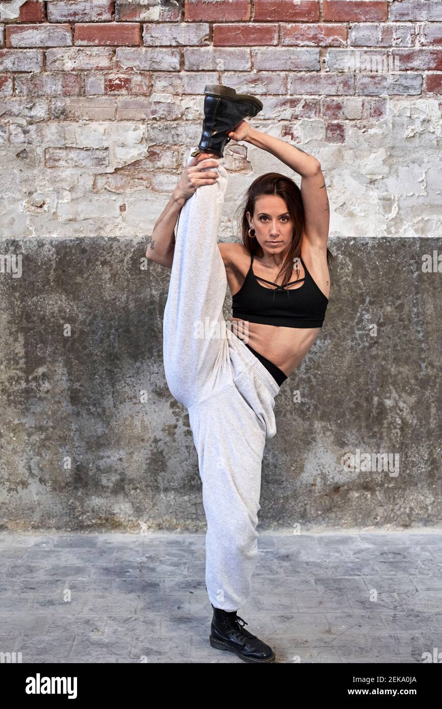 Danseuse moyenne adulte pratiquant contre le vieux mur de briques à l'intérieur usine Banque D'Images
