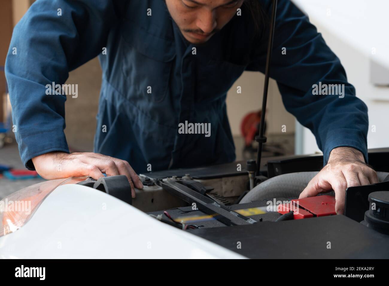 Mécanicien professionnel fournissant des services de réparation et d'entretien de voitures dans le garage automobile. Concept d'affaires de service de voiture. Banque D'Images